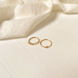 Close-up of two elegant golden knot rings featuring minimalist intertwining design