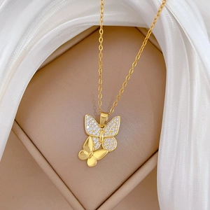 Macro view of twin butterfly pendant with cubic zirconia on gold plated chain necklace