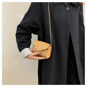 Detail of crocodile embossed leather mini bag with gold chain strap and envelope flap