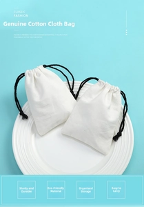 Detail of white cotton drawstring jewelry pouches with natural woven texture and black cords