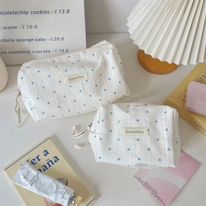 Macro detail of striped canvas makeup bags with blue heart pattern and zipper ribbons