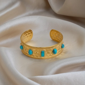 Nahaufnahme einer gehämmerten 18K vergoldeten Manschette mit Vintage-Türkisen auf weißem Satin