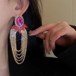 Detail of luxury long tassel earrings featuring a large purple oval stone with rhinestones