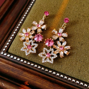 Close-up of vintage gold flower earrings with pink rhinestones and star charms