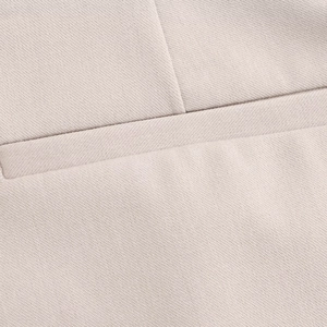 Detailed close-up of beige trousers showing high-quality fabric texture and pocket stitching