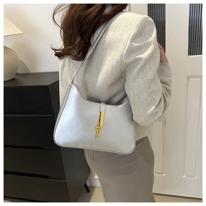 Model wearing silver underarm bag with gold metal clasp showing actual size and fit