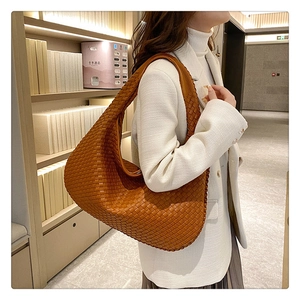 Detail view of woven leather texture on a brown caramel hobo bag worn by model