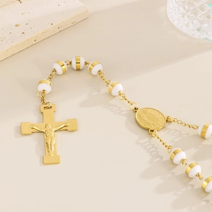 Detailed close-up of 18K gold-plated rosary necklace with white beads and crucifix