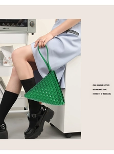 Close-up of green hand-woven triangle handbag showing diamond lattice texture and handle