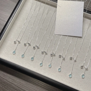 S925 Sterling Silver necklace with blue teardrop pendants displayed on a beige jewelry tray