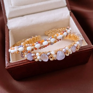 Macro detail of handmade 18K gold plated wire wrapped bangles with pearls and amethysts