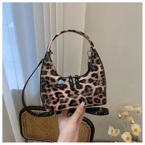 Detail of pink leopard print patent leather handbag with dual zipper and crescent shape