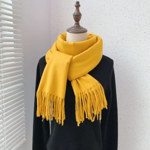 Detail of yellow cashmere-like scarf with tassels displayed on a mannequin