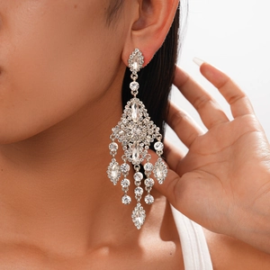 Close-up of oversized rhinestone flower tassel earrings worn by a model in studio