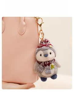Detail of plush penguin keychain with red knitted scarf on a pink leather bag