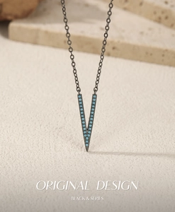 Macro detail of V-shaped turquoise inlay pendant with black gunmetal finish chain