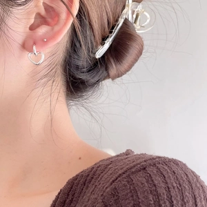 Model wearing sterling silver hollow heart earrings in a warm lifestyle setting