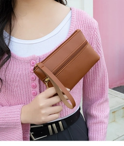 Close-up of brown textured leather wristlet bag featuring dual golden zippers and strap