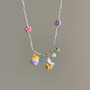 Beaded necklace with floral pendants and honeybee charms on a neutral background