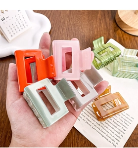 Close-up of small acetate hair claws in assorted colors on a warm wooden background