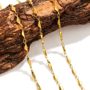 Modern gold geometric necklace with rhombus links displayed on a natural tree bark background