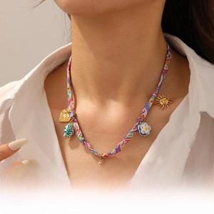 Détail d'un collier tissé coloré avec des pendentifs étoile de mer, soleil et poisson