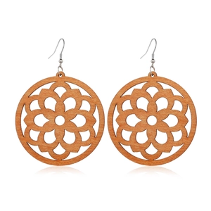 Detailed close-up of brown wooden earrings featuring an intricate hollow mandala pattern