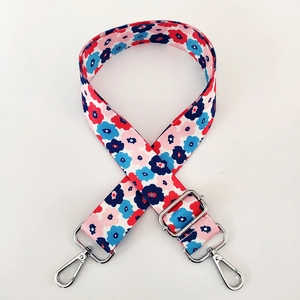 Detail of colorful floral fabric shoulder strap with silver metal buckles and adjusters
