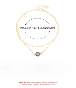 Detail of gold double-layer anklet with blue evil eye pendant and sizing specs