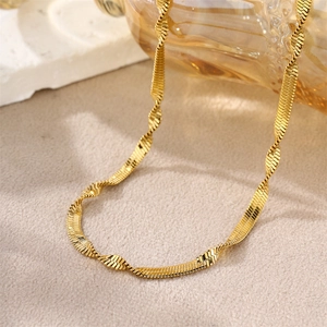 Macro detail of golden flat snake chain necklace with creative twisted weave design