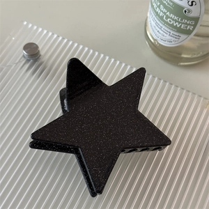 Detailed view of large black star hair claw clip with fine glitter and acrylic texture