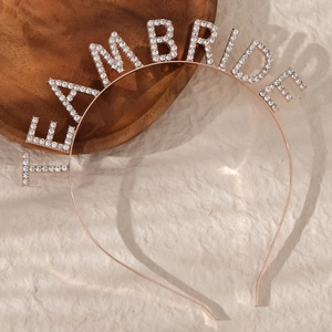 Close-up of rose gold Team Bride headband with sparkling rhinestones on beige surface