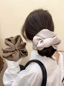 Close-up of oversized satin hair scrunchies in coffee and grey on a ponytail