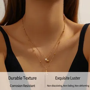 Detail of layered gold necklace with starfish shell charms and pearl on a model
