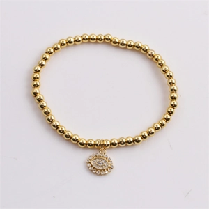 Detail of gold beaded elastic bracelet featuring a micro-set zircon Evil Eye pendant