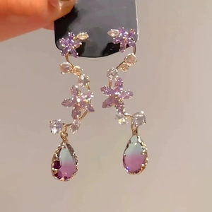Close-up of floral crystal earrings with purple gems and gradient drop pendants