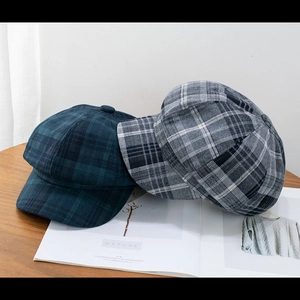 Close-up of checkered newsboy caps in green and grey on a rustic wooden table