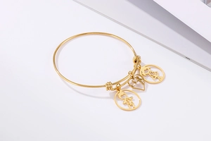 Detail of 18k gold plated stainless steel bangle with boy girl and heart pendants