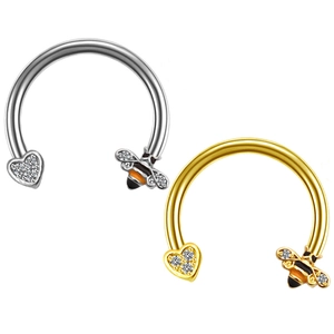 Detailed view of silver and gold horseshoe nose rings with crystal heart and bee charms