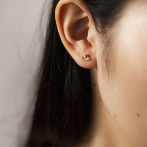 Elegant gold leaf-shaped stud earrings with crystal stones worn by a model