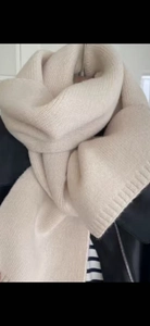Detail of soft beige knitted scarf texture showing thick thermal material on a model
