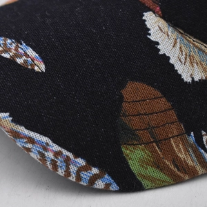 Cotton baseball cap with colorful feather print on black fabric showing twill texture
