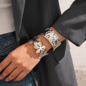 Dettaglio del bracciale a fiori argentato e polsino martellato su modella donna