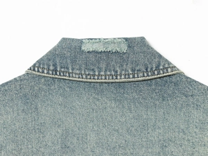 Detailed close-up of distressed collar on light blue loose fit denim jacket