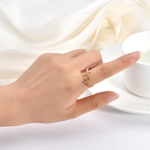 Close-up of golden three-layer bead wrap ring on hand with elegant silk background