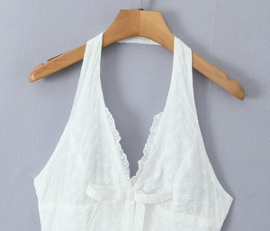 Close-up of white cutout embroidery halter dress with bow detail and textured fabric