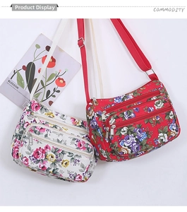 Detail showing two floral printed crossbody bags with multiple zipper pockets and straps