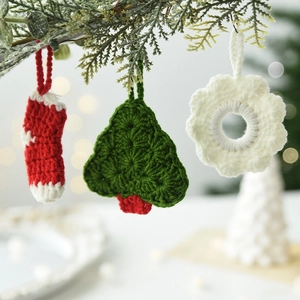 Set di ornamenti natalizi all'uncinetto con albero, fiocco e calza su un ramo di pino