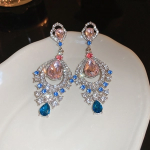 Macro detail of vintage fan-shaped drop earrings with pink stones on a white tray