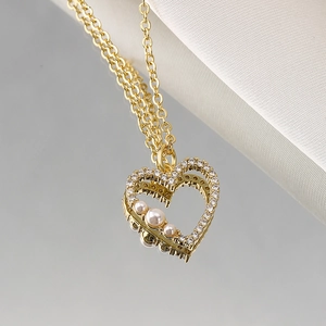 Elegant gold heart pendant necklace featuring zircon pavé and pearl accents